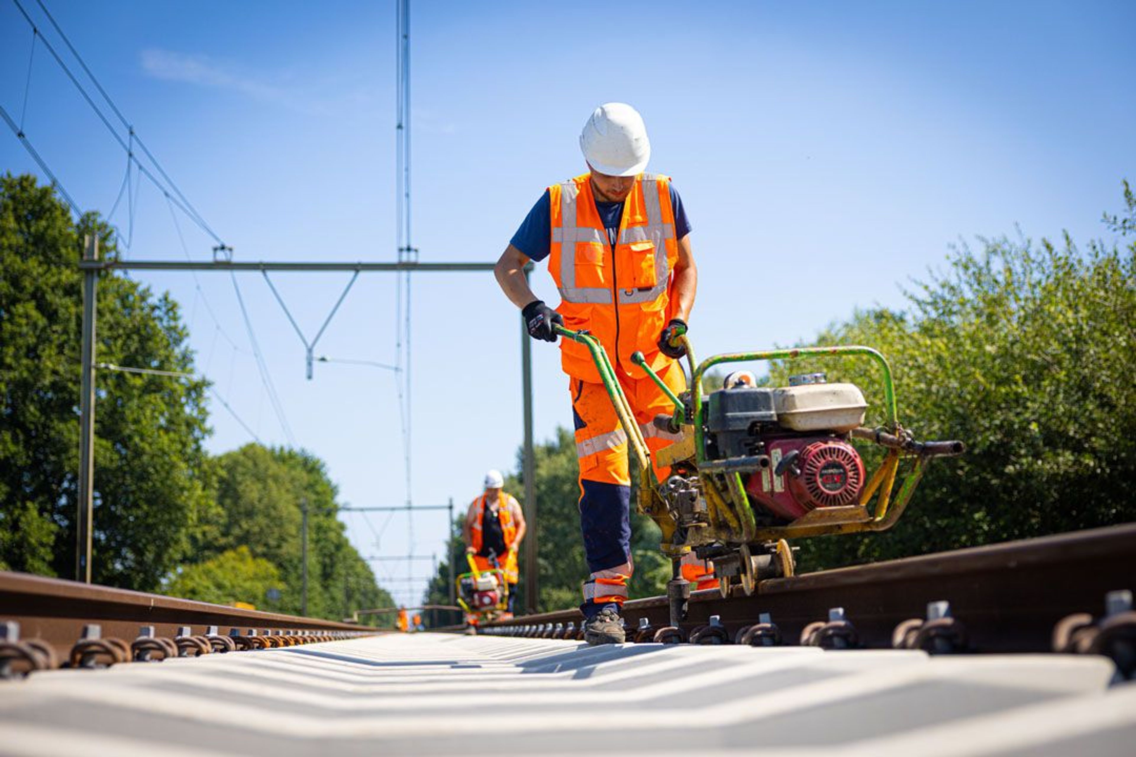 Werknemers aan het spoor met een railverharder.