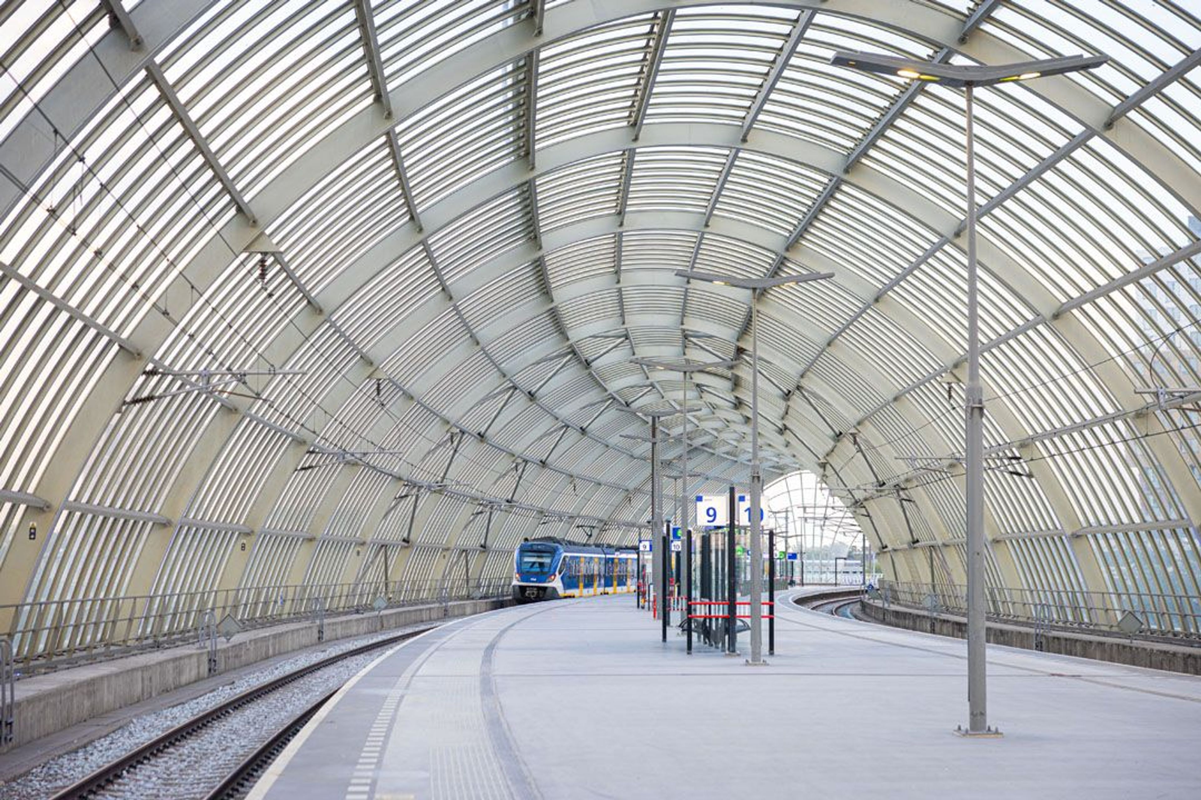 Moderne treinstation met gebogen dak en spoorrails.