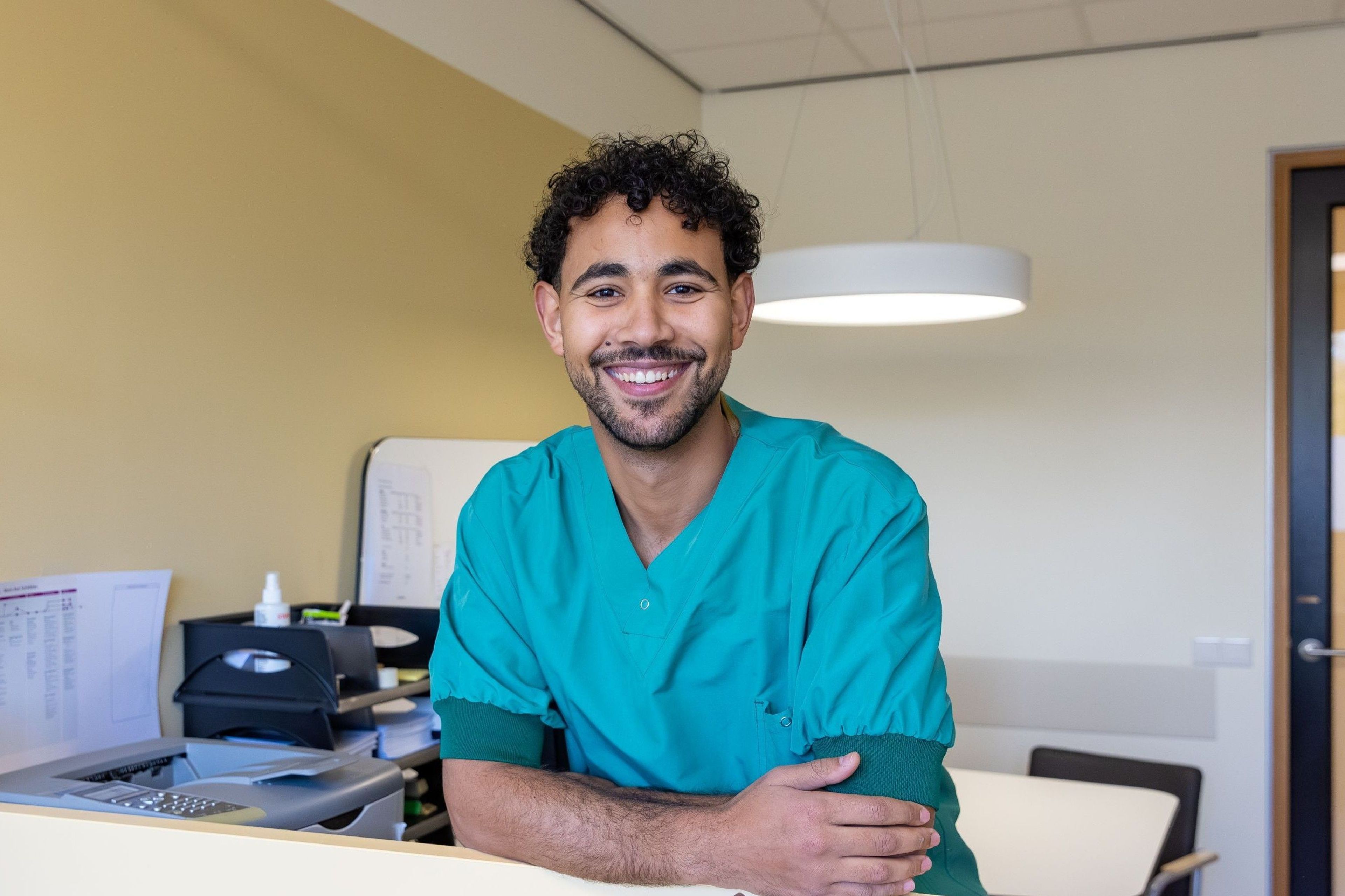 Vriendelijke zorgprofessional in groene scrubs.