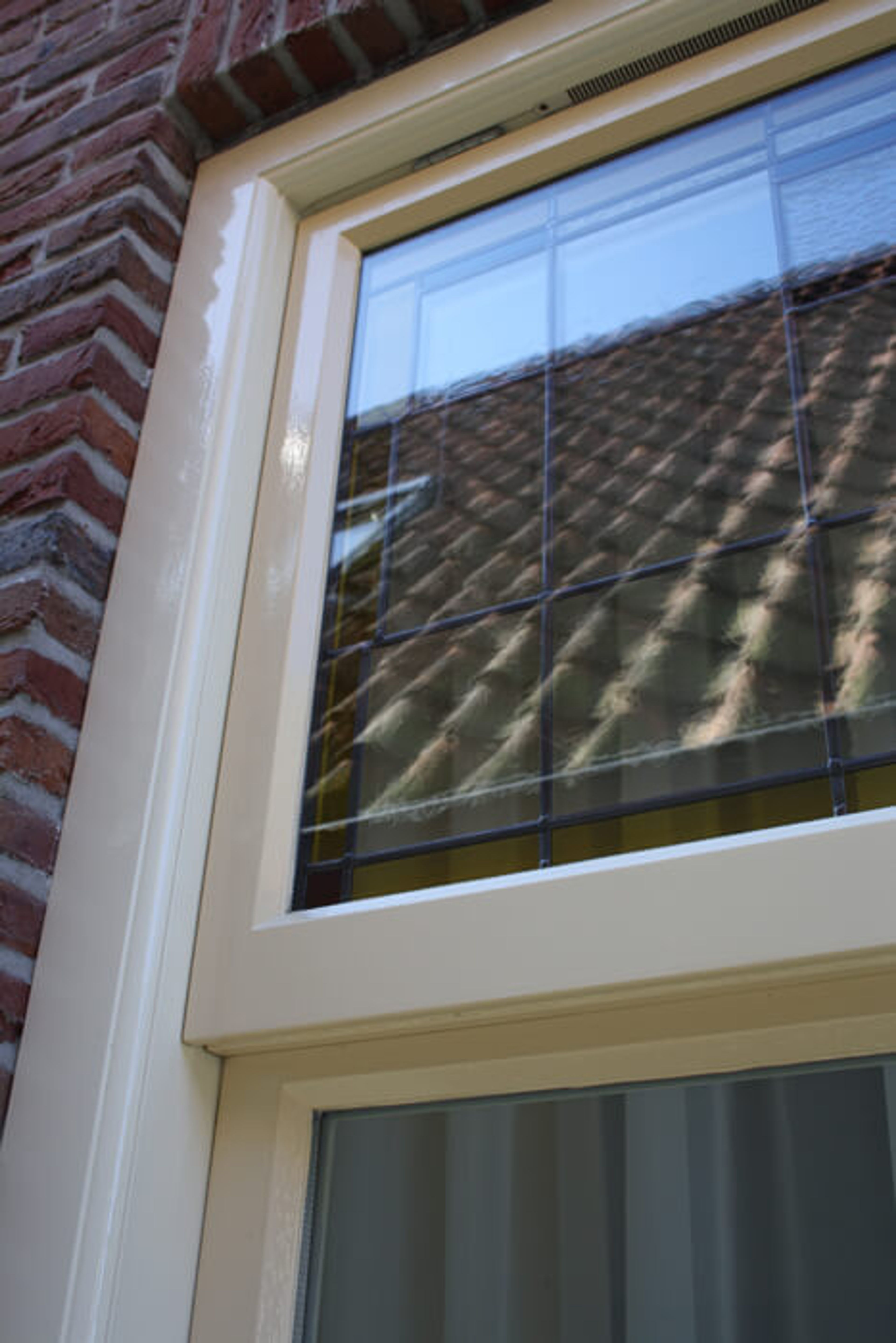 Detail van een vers geschilderd kozijn met glas-in-lood