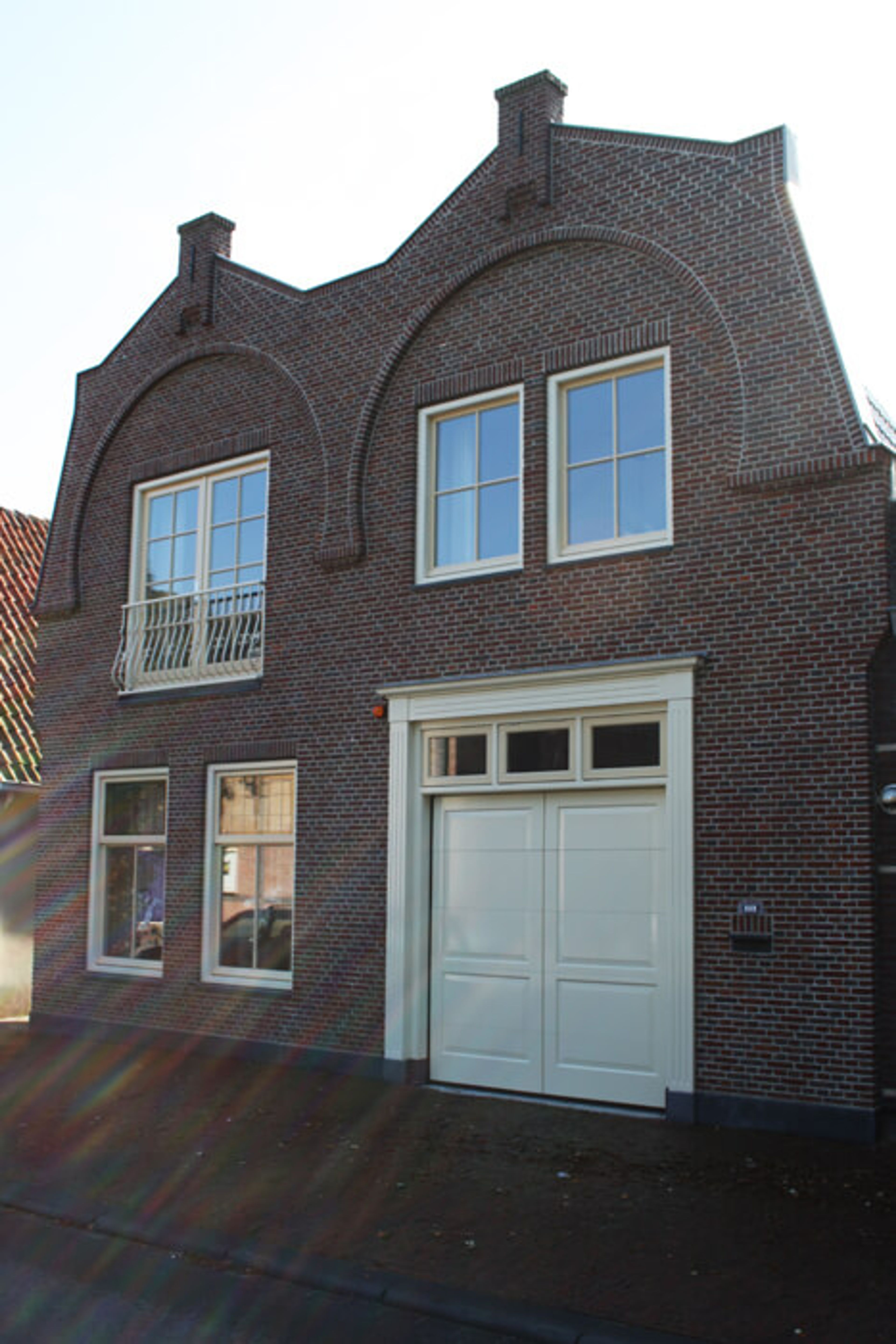 Herenhuis met licht geschilderde kozijnen en dubbele garagedeuren