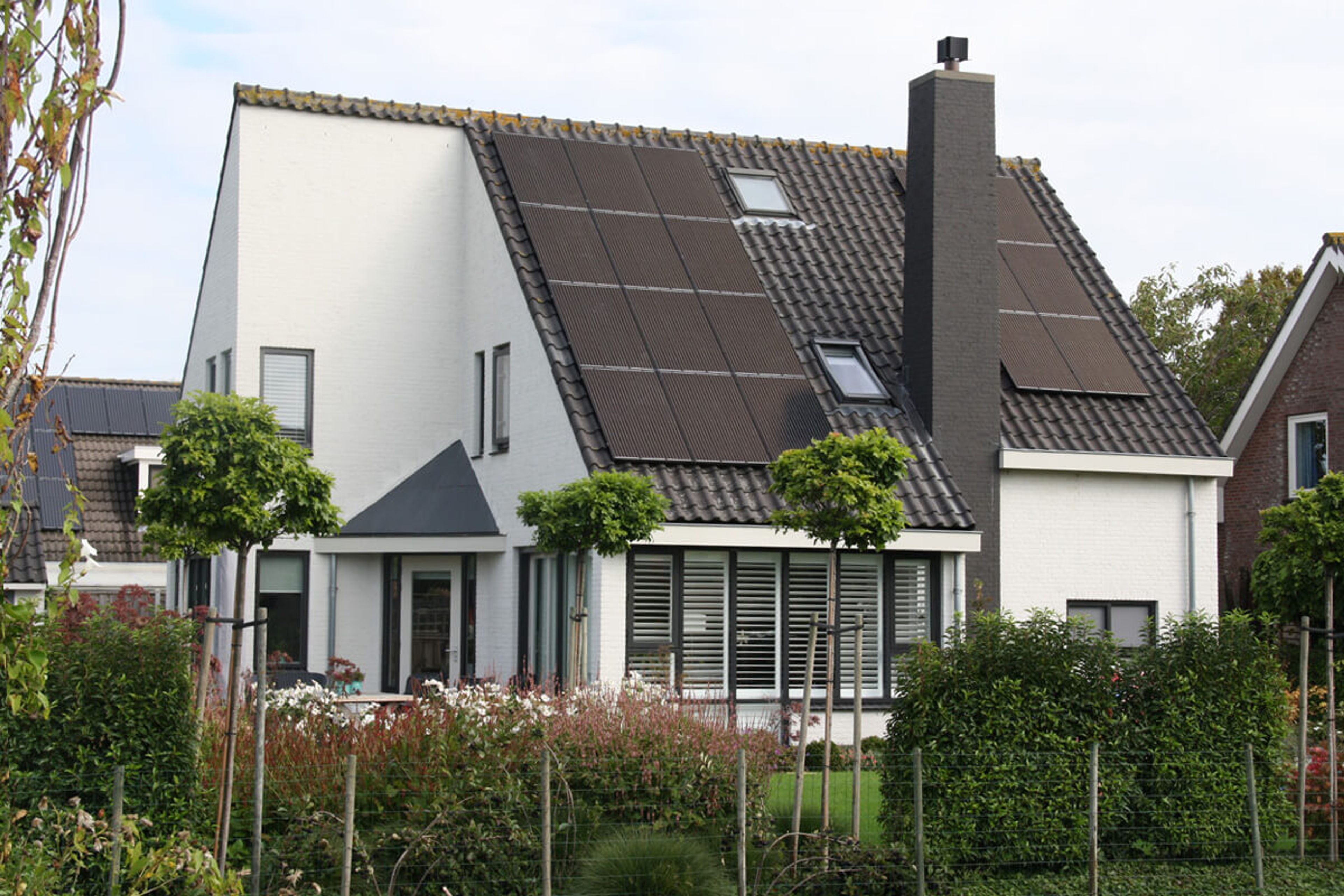 Wit geschilderde vrijstaande woning met donkere kozijnen en shutters