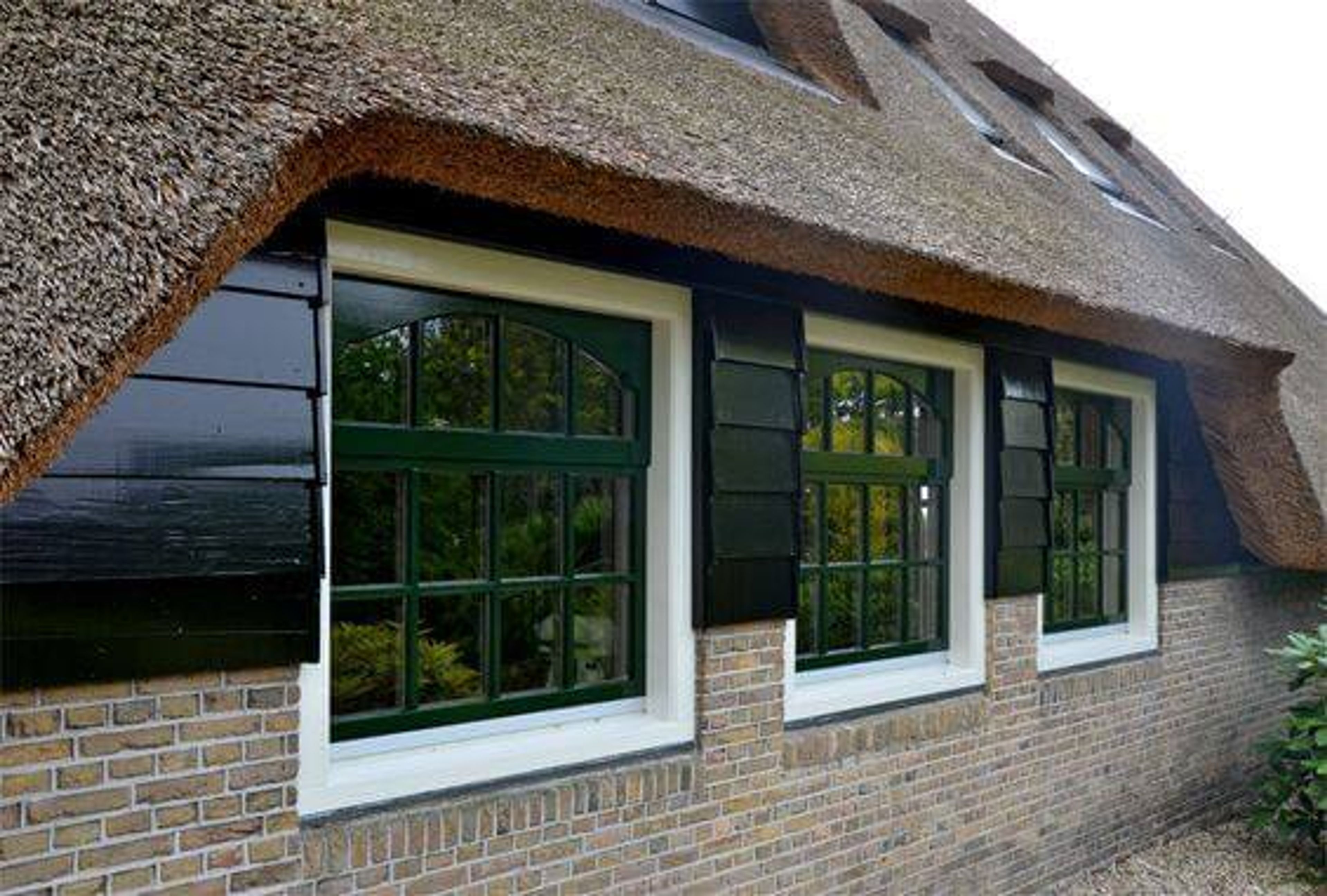 Rietgedekte woning met donkergroen geschilderde kozijnen en luiken