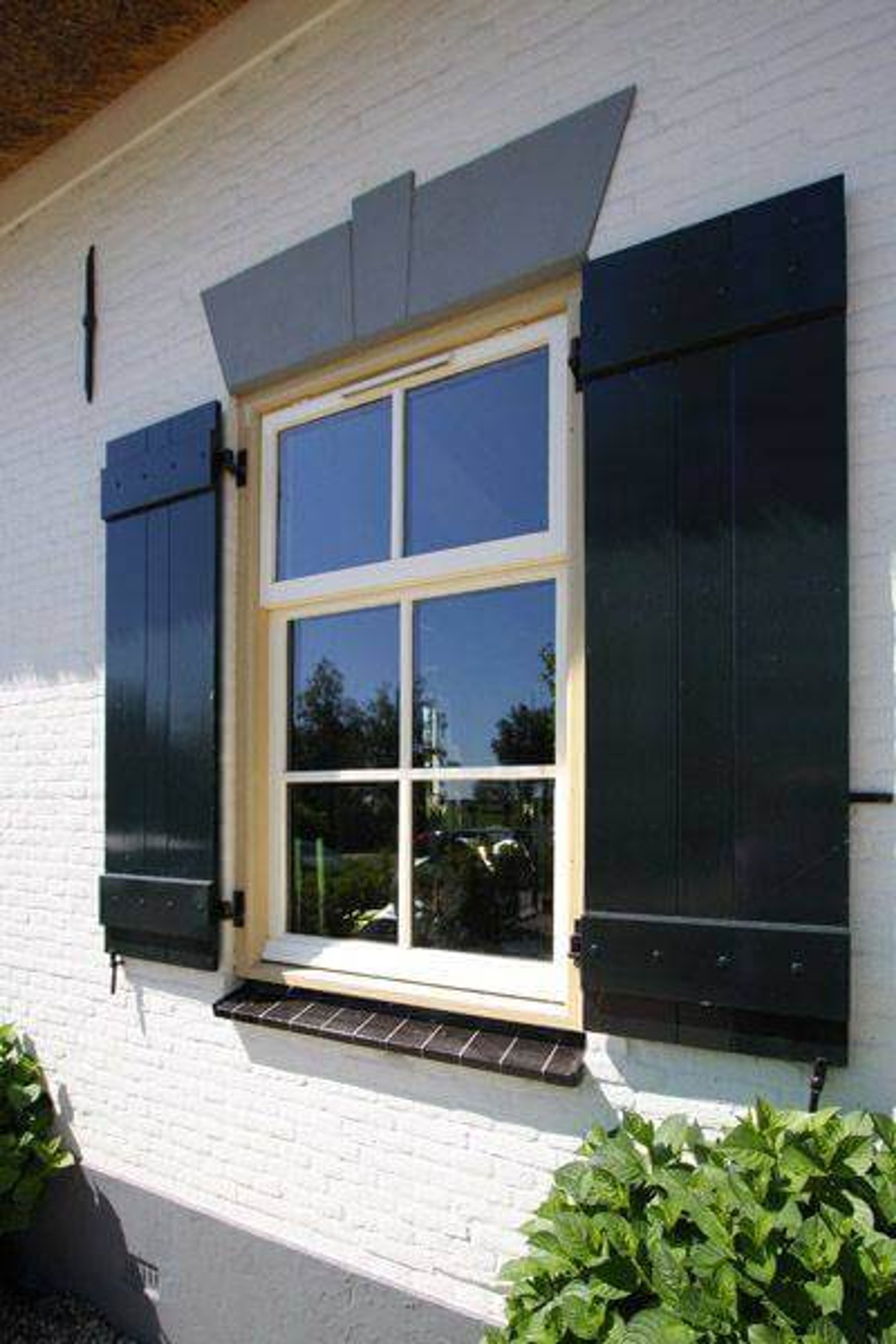 Witte woning met zwart geschilderde luiken en houten kozijn