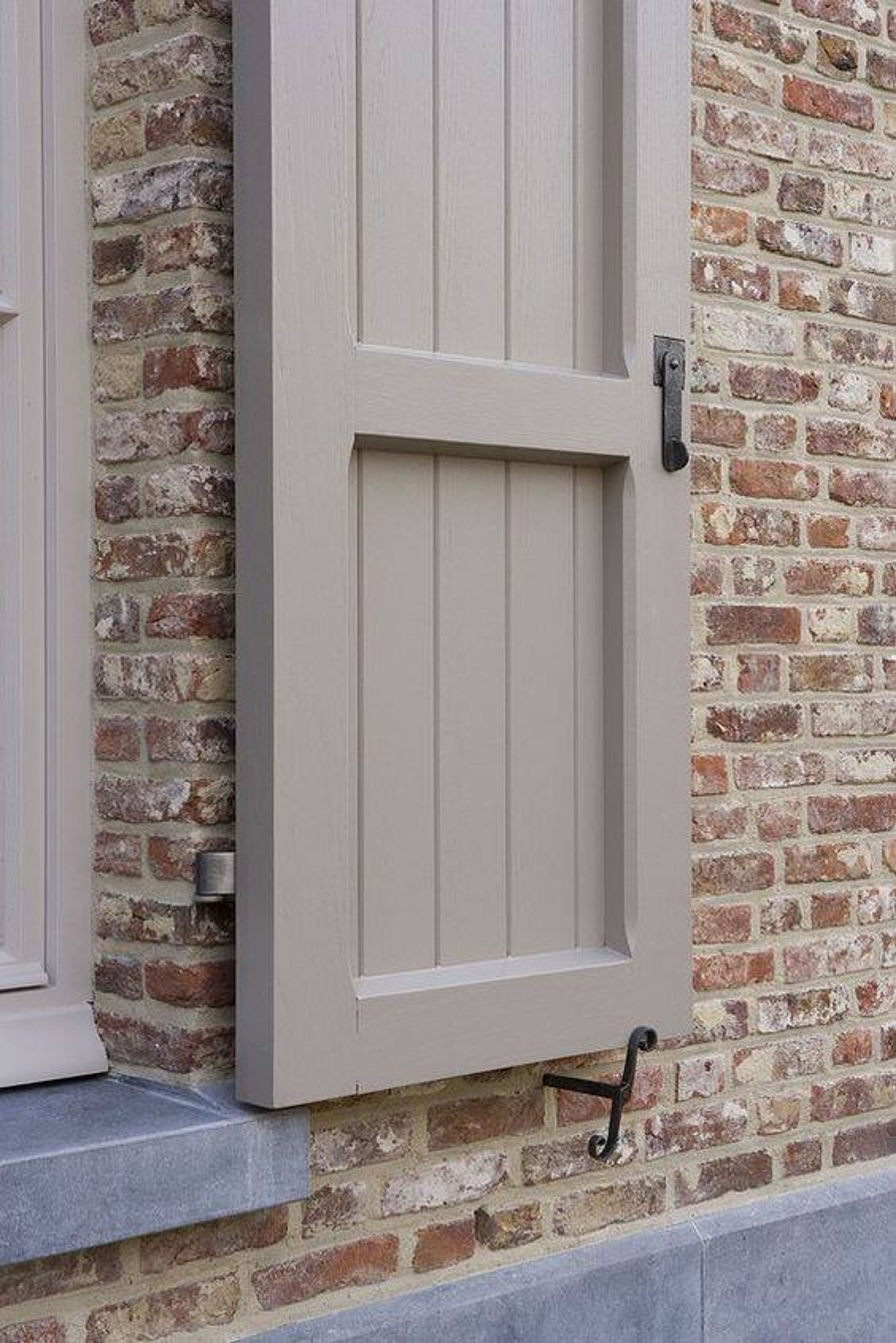 Detail van een geschilderd houten luik tegen een bakstenen gevel