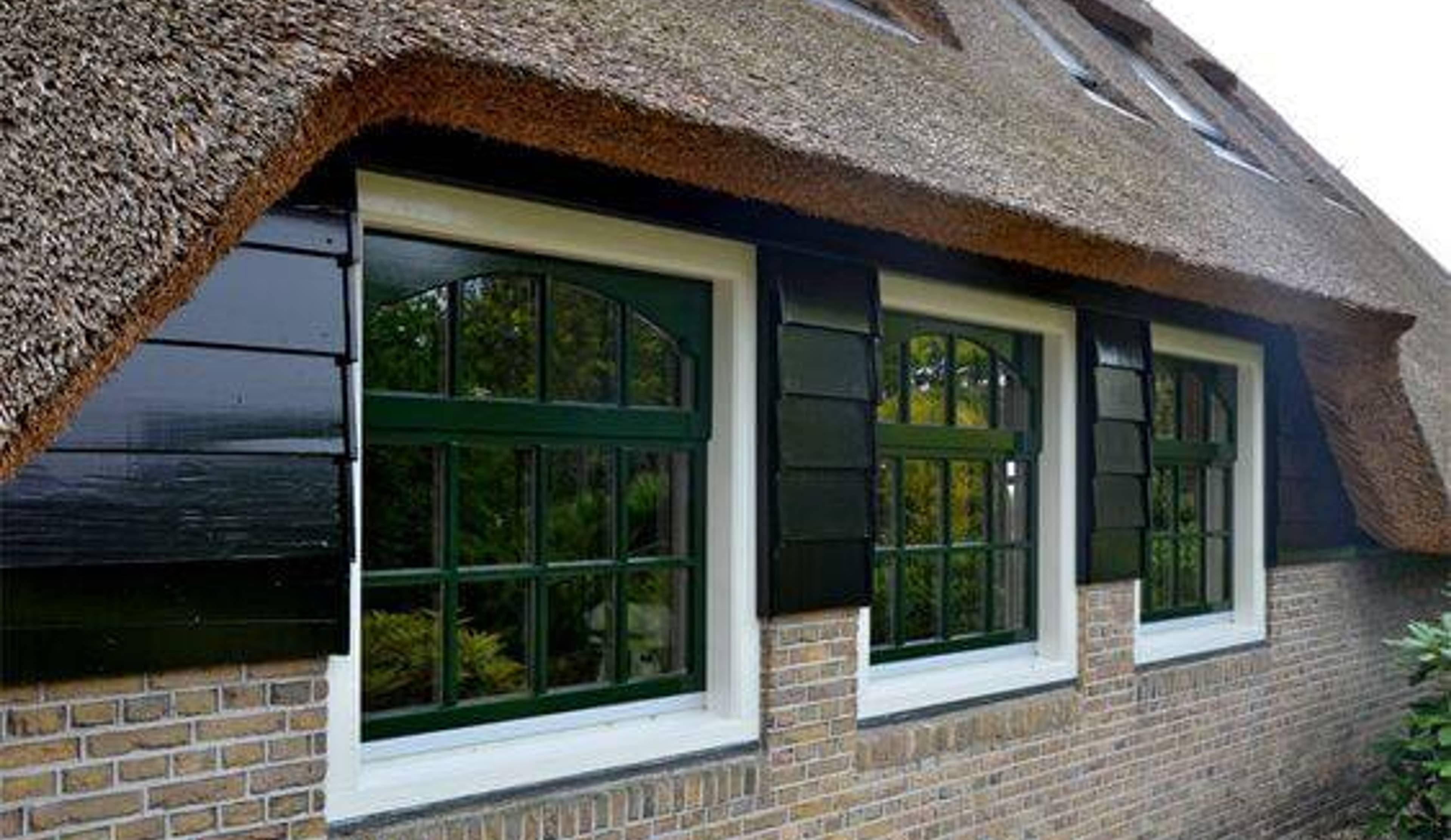 Rietgedekte woning met donkergroen geschilderde kozijnen en luiken
