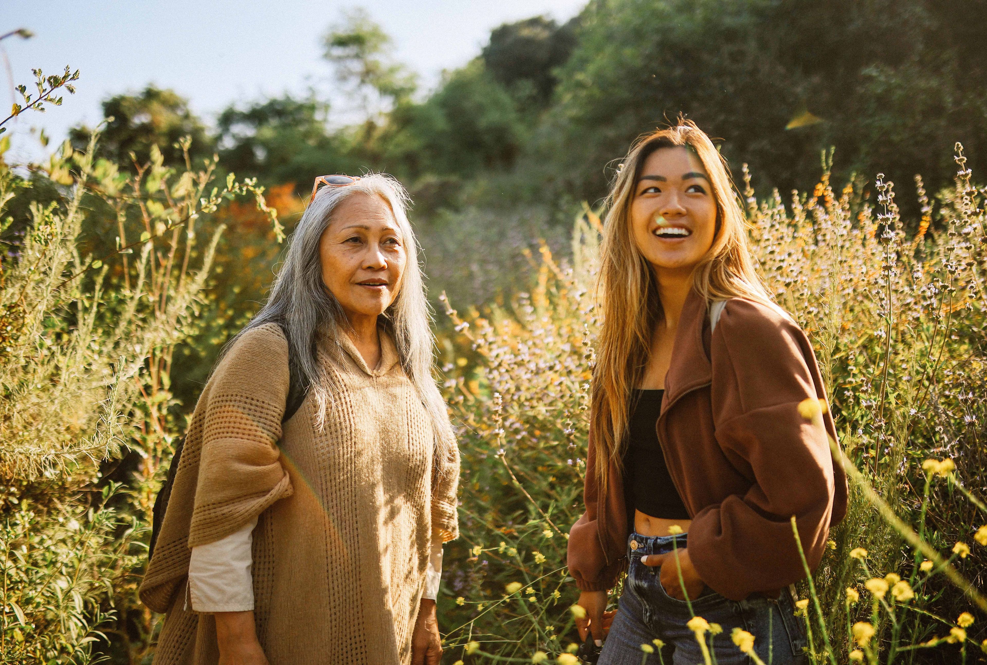 Twee vrouwen lachen in een veld met bloemen.