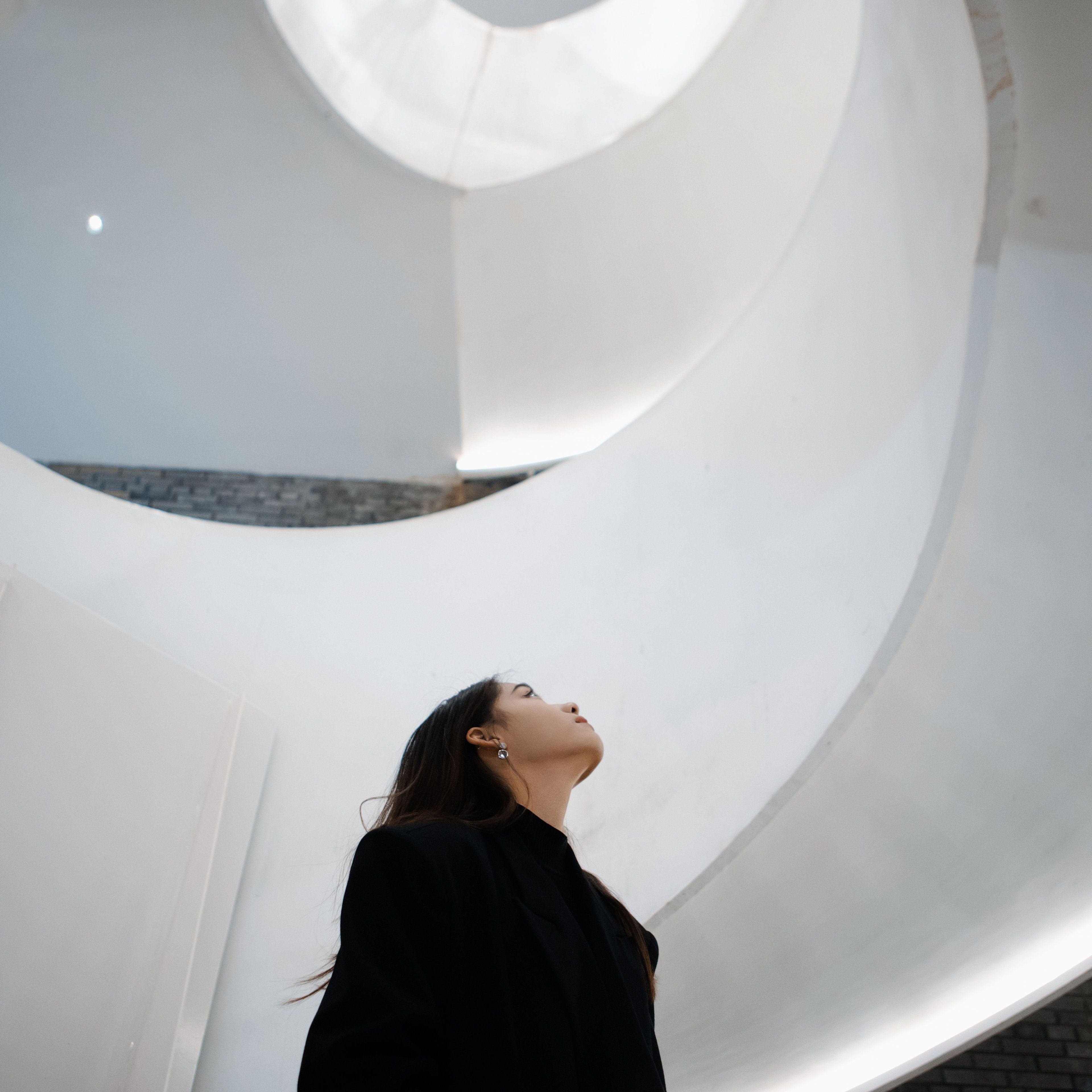 Vrouw kijkt omhoog in moderne architectuur.