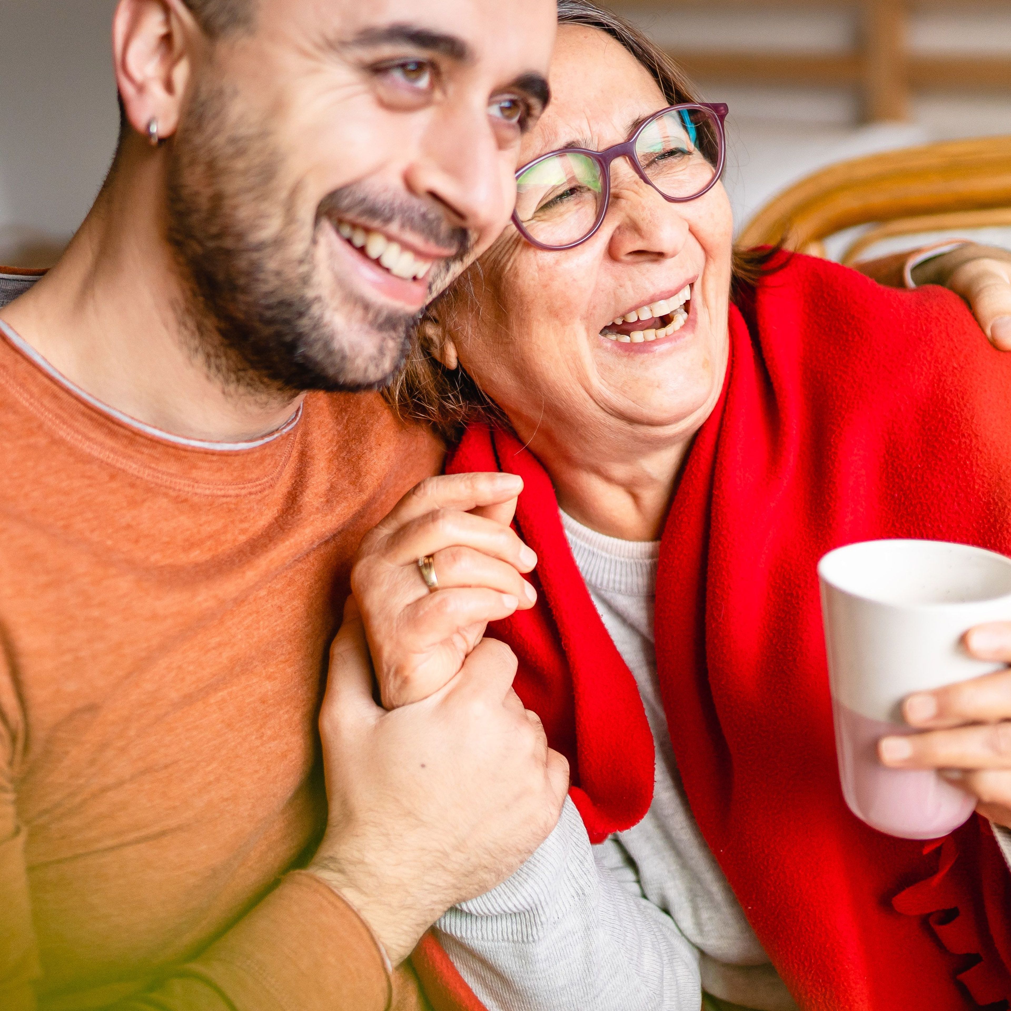 Een man en een vrouw lachen samen, knuffelend.