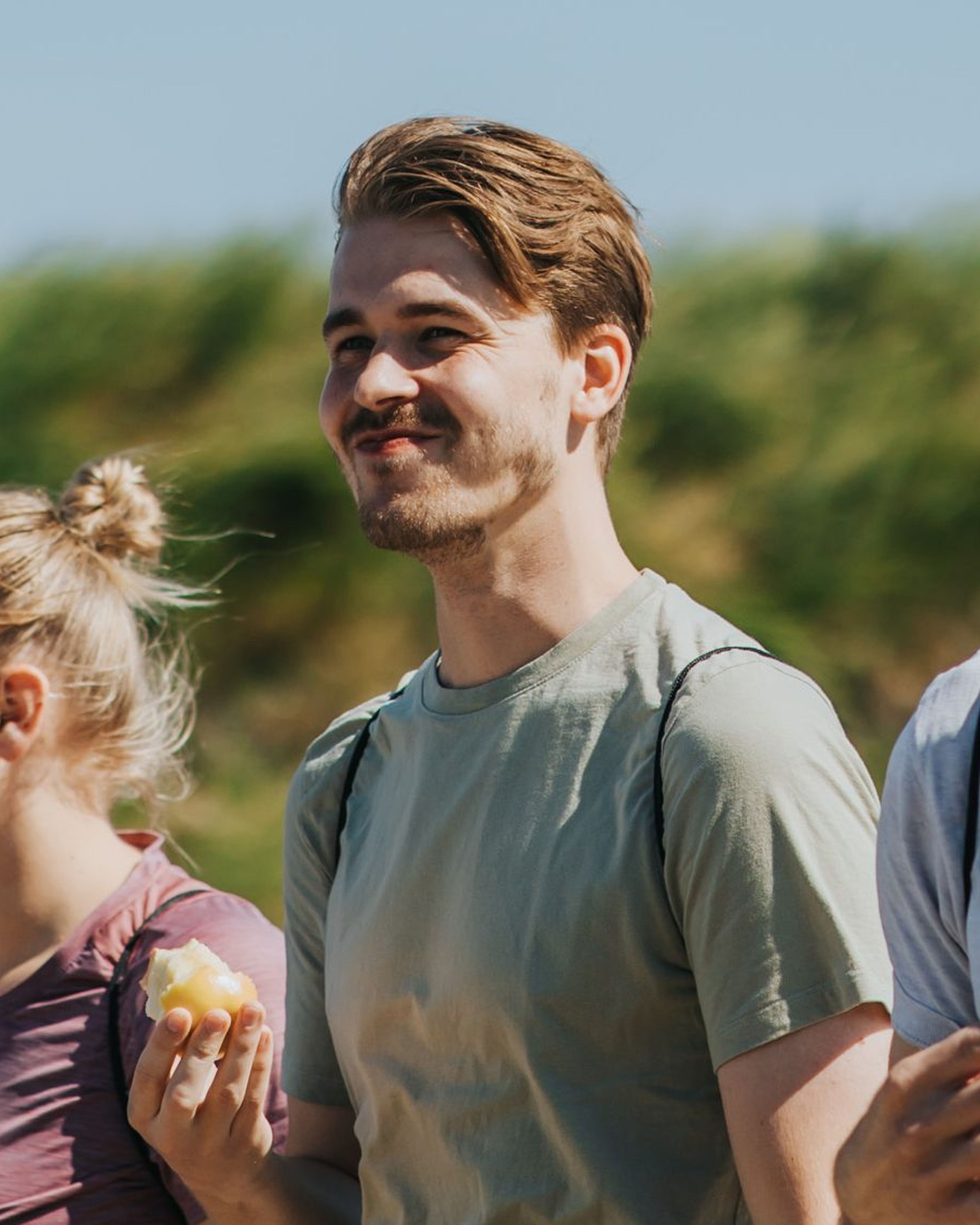 Jongeman met een appel, lachend tijdens een wandeling.