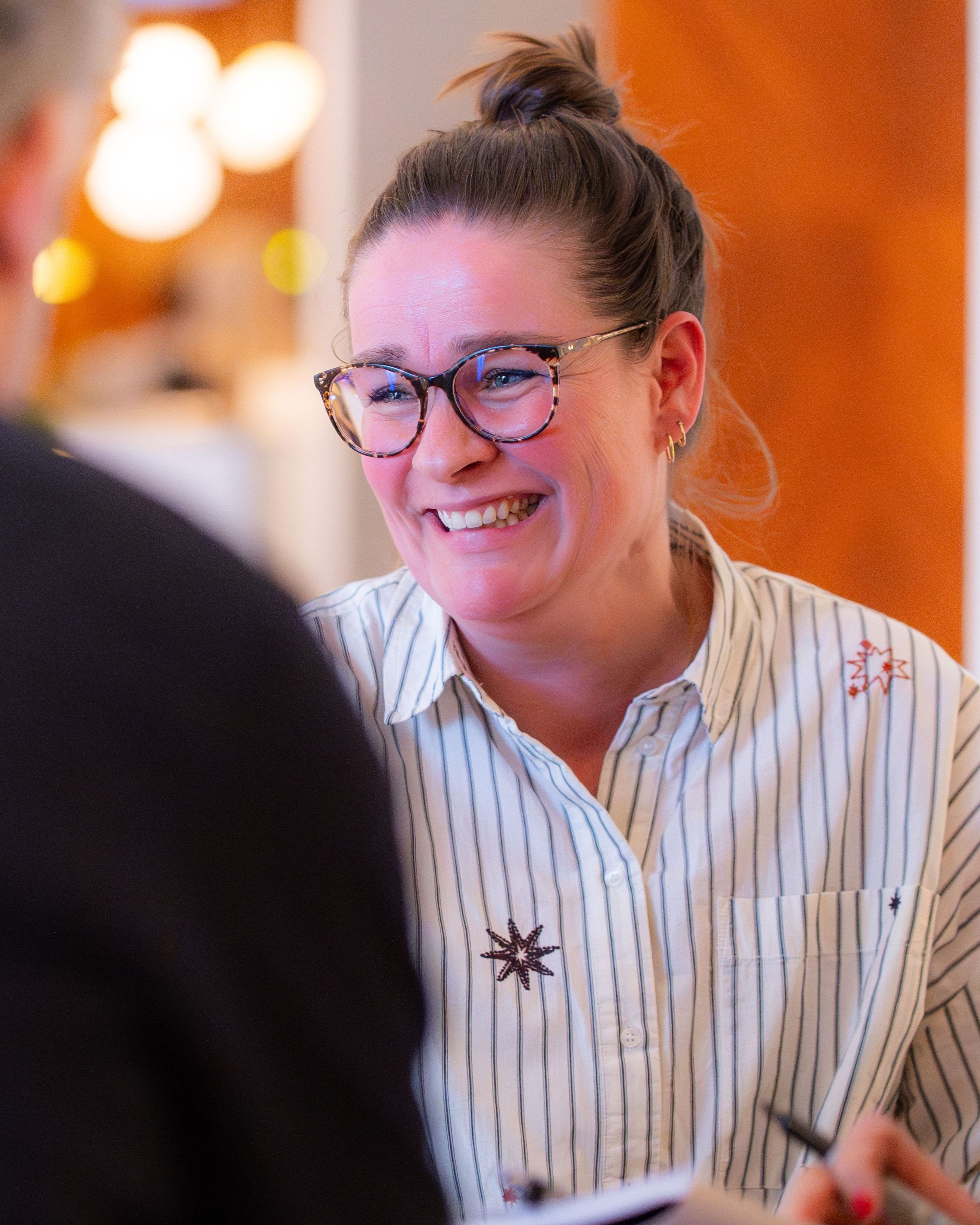 Vrouw met brillen en een glimlach in gesprek.