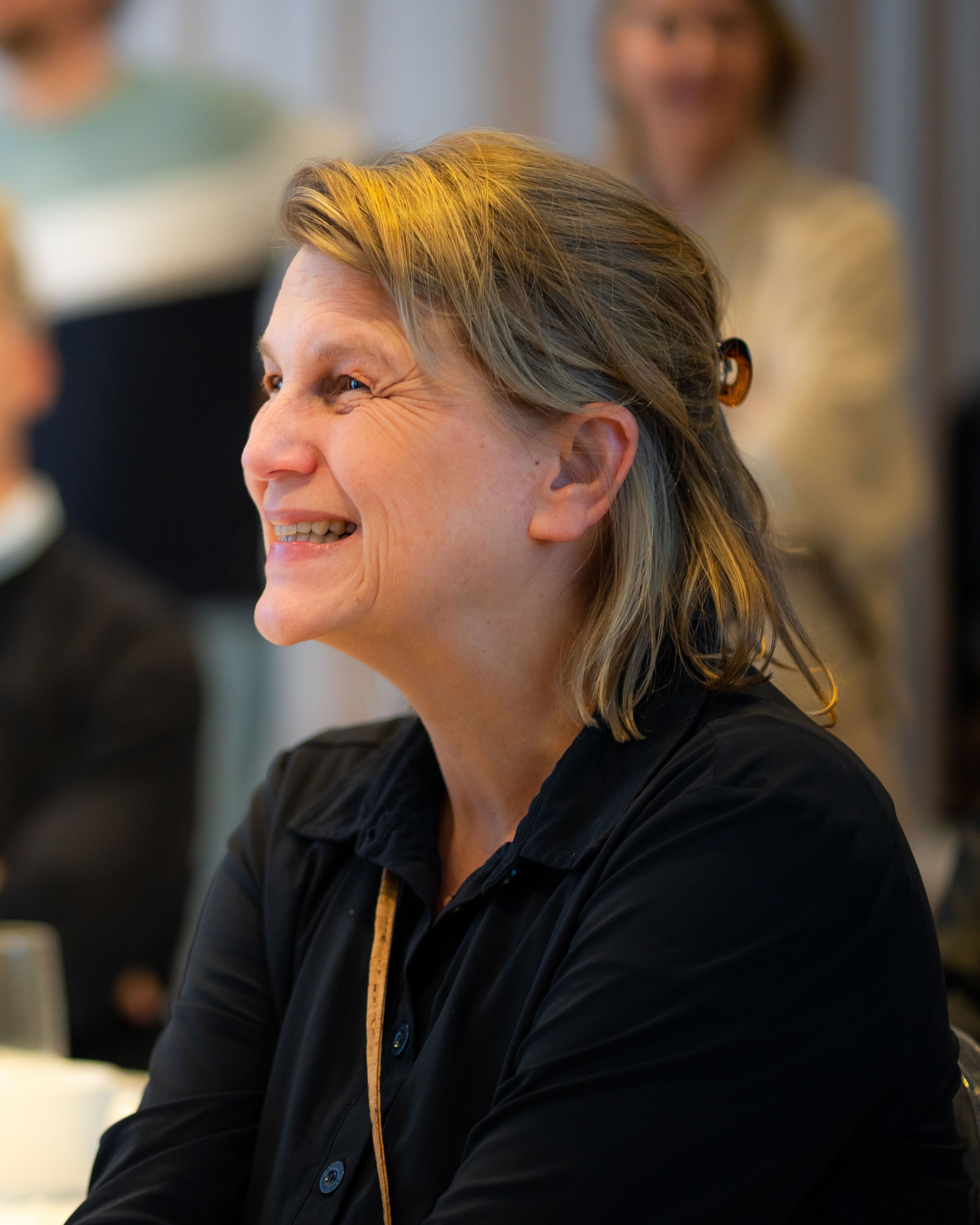 Vrouw met een glimlach aan tafel.