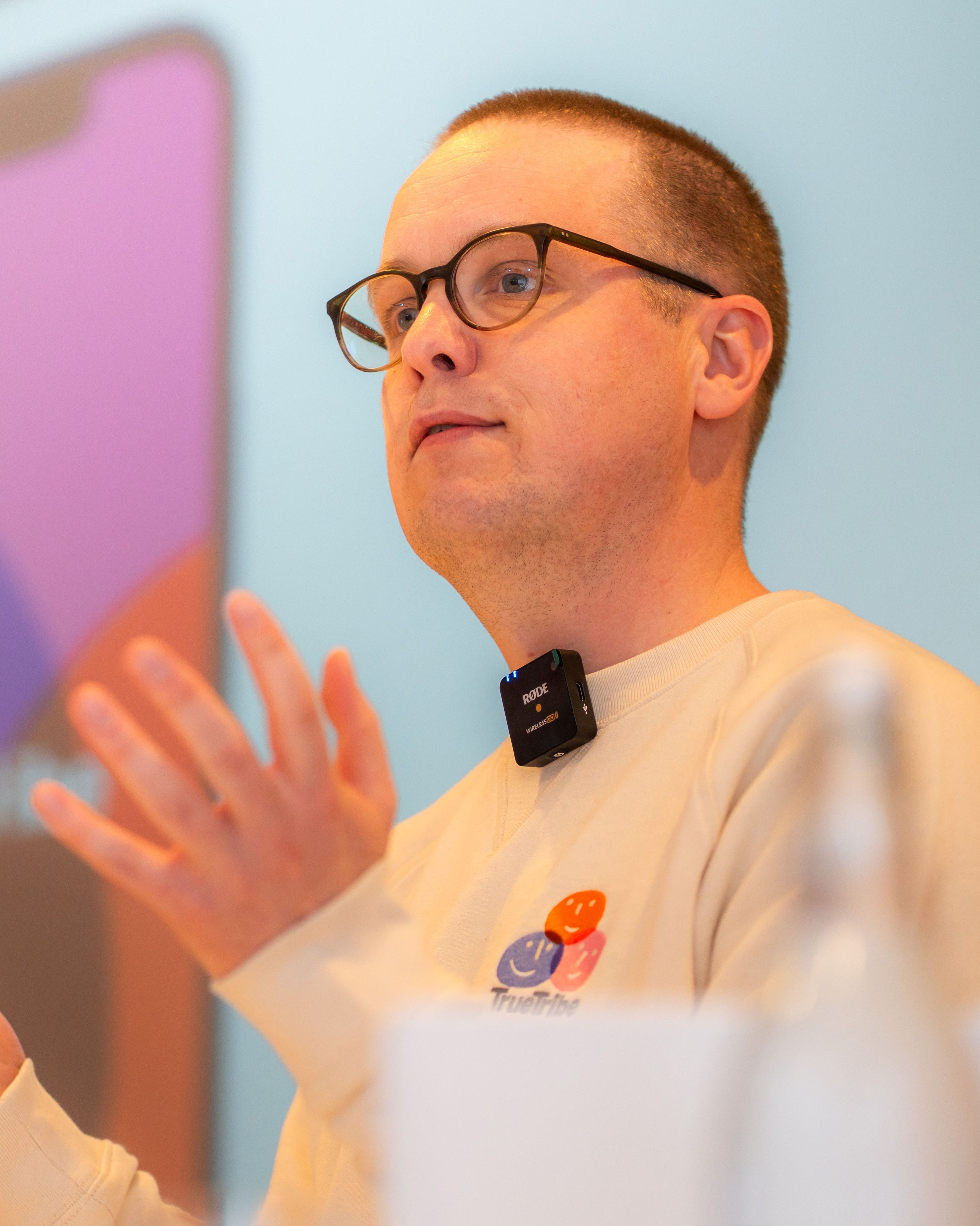 Man met bril en microphone, presentatietekens.