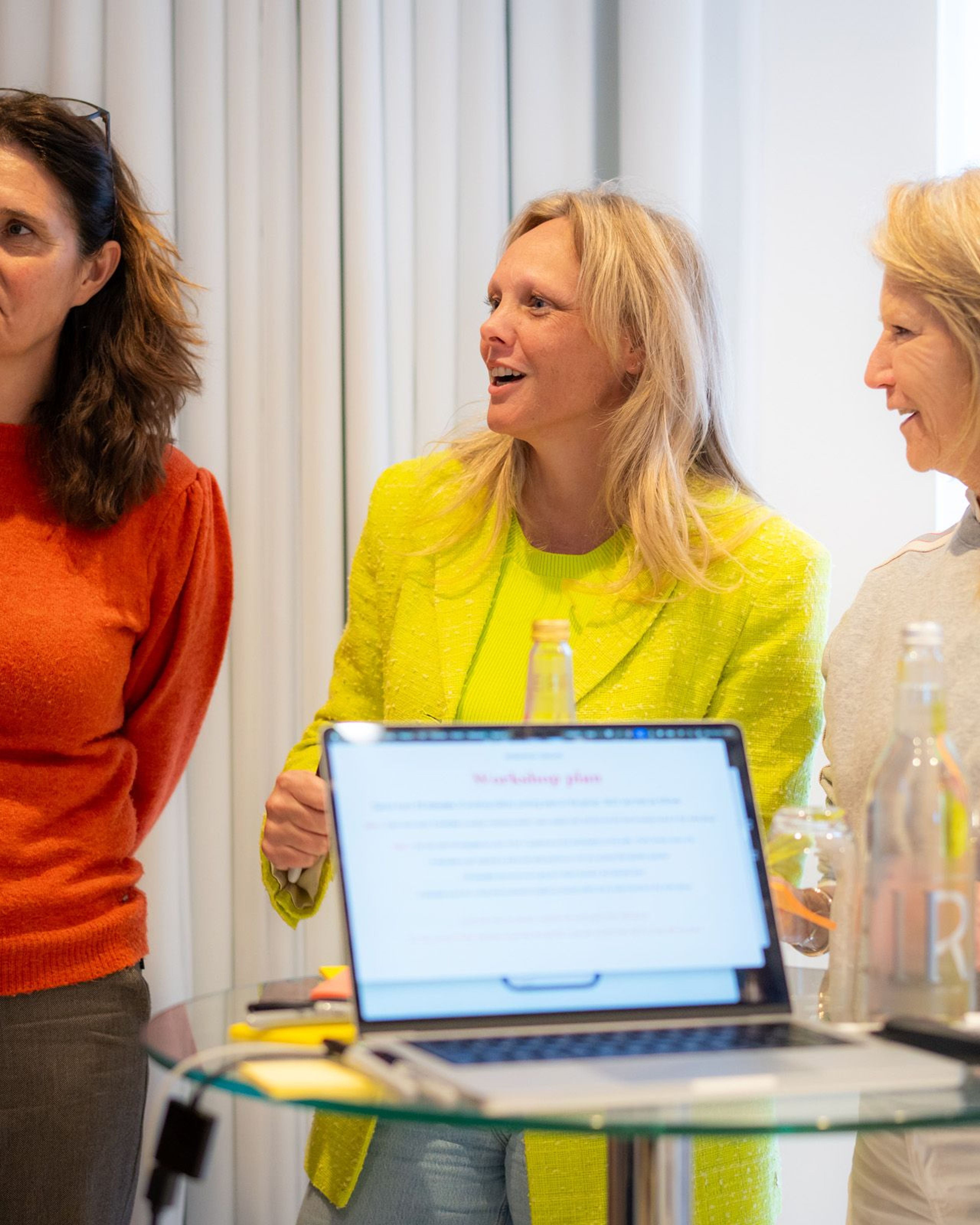 Drie vrouwen in gesprek bij een workshop.