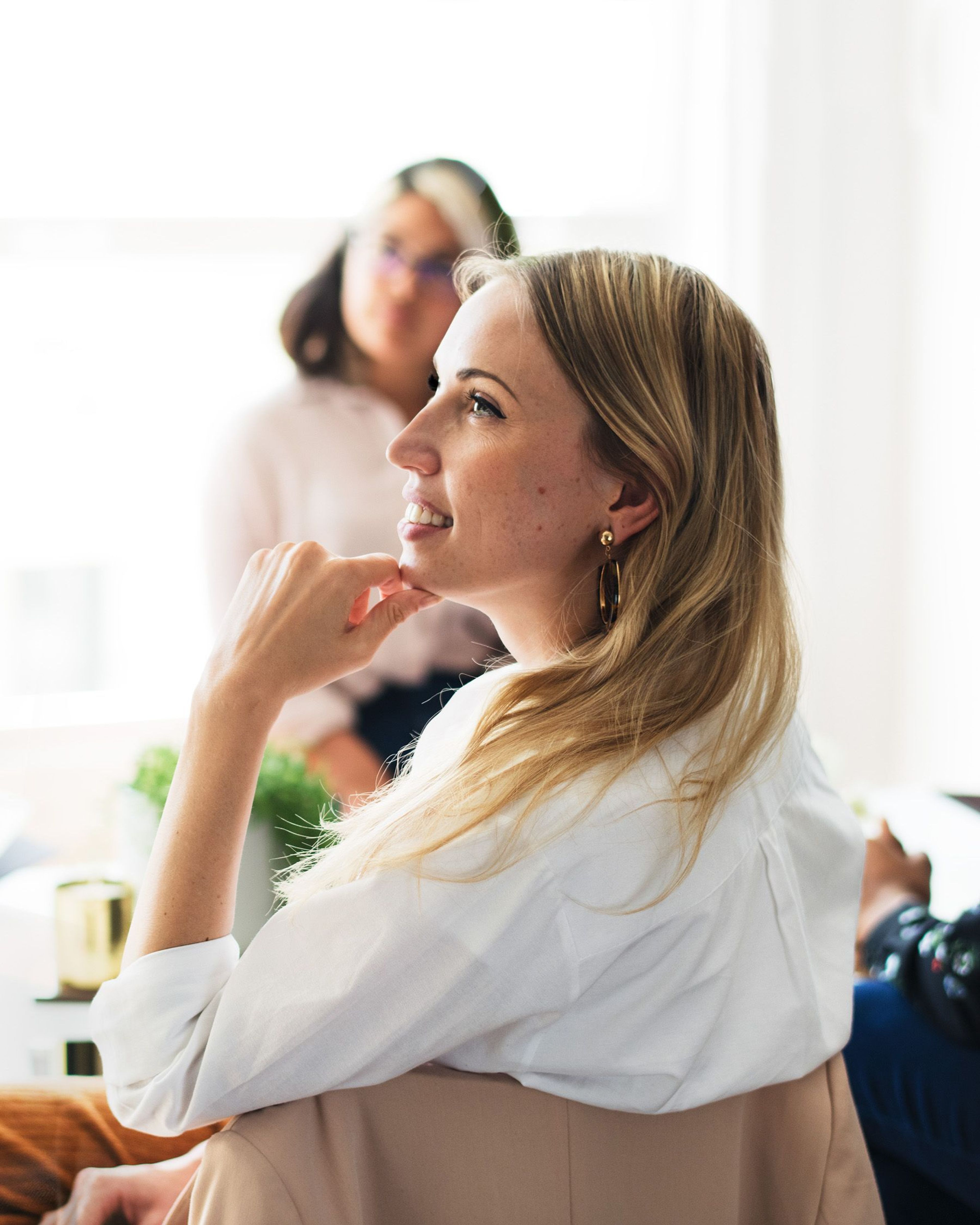 Vrouw met blond haar, in gedachten verzonken, in een vergadering.