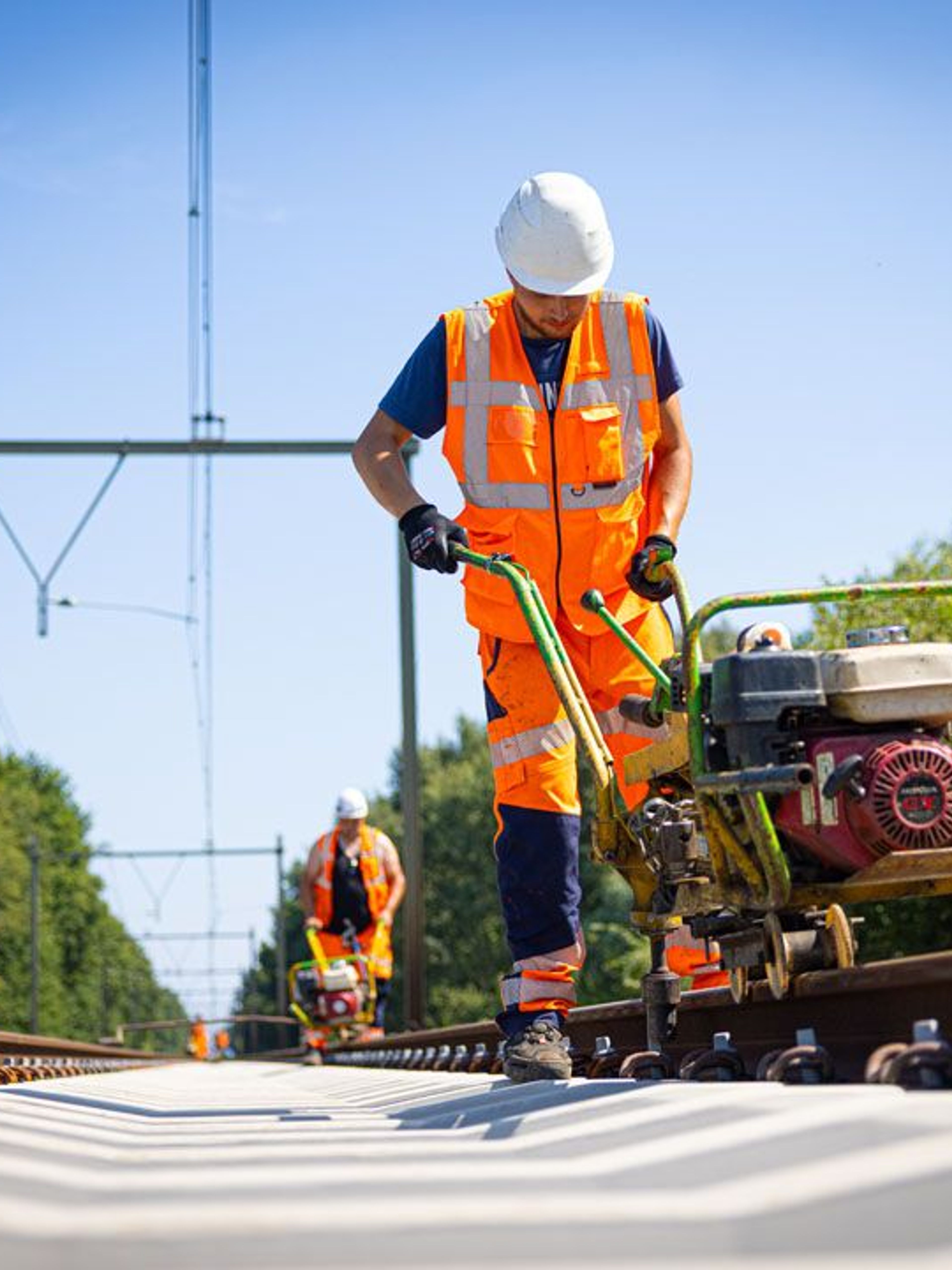 Werknemers aan het spoor met een railverharder.