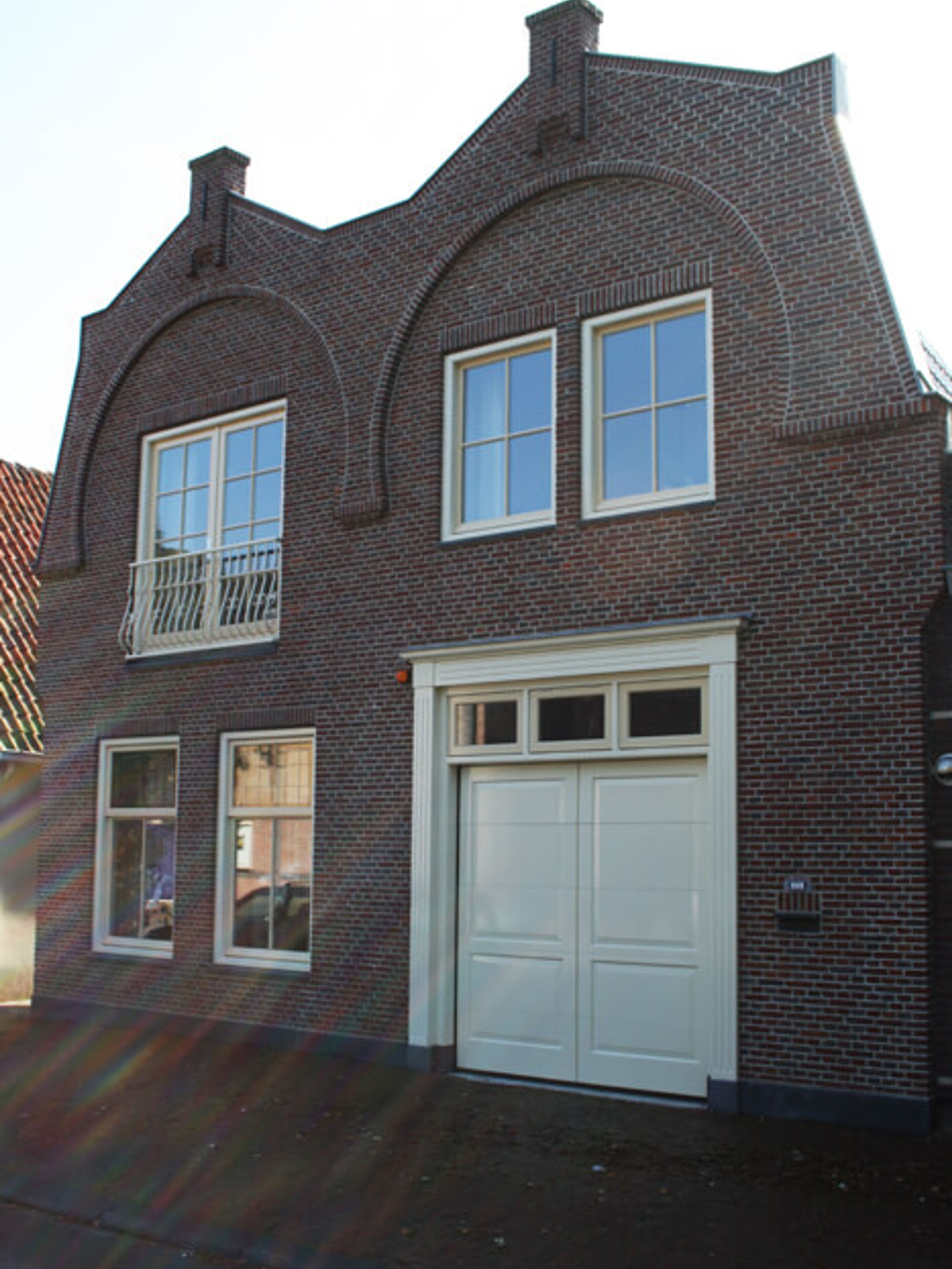 Herenhuis met licht geschilderde kozijnen en dubbele garagedeuren