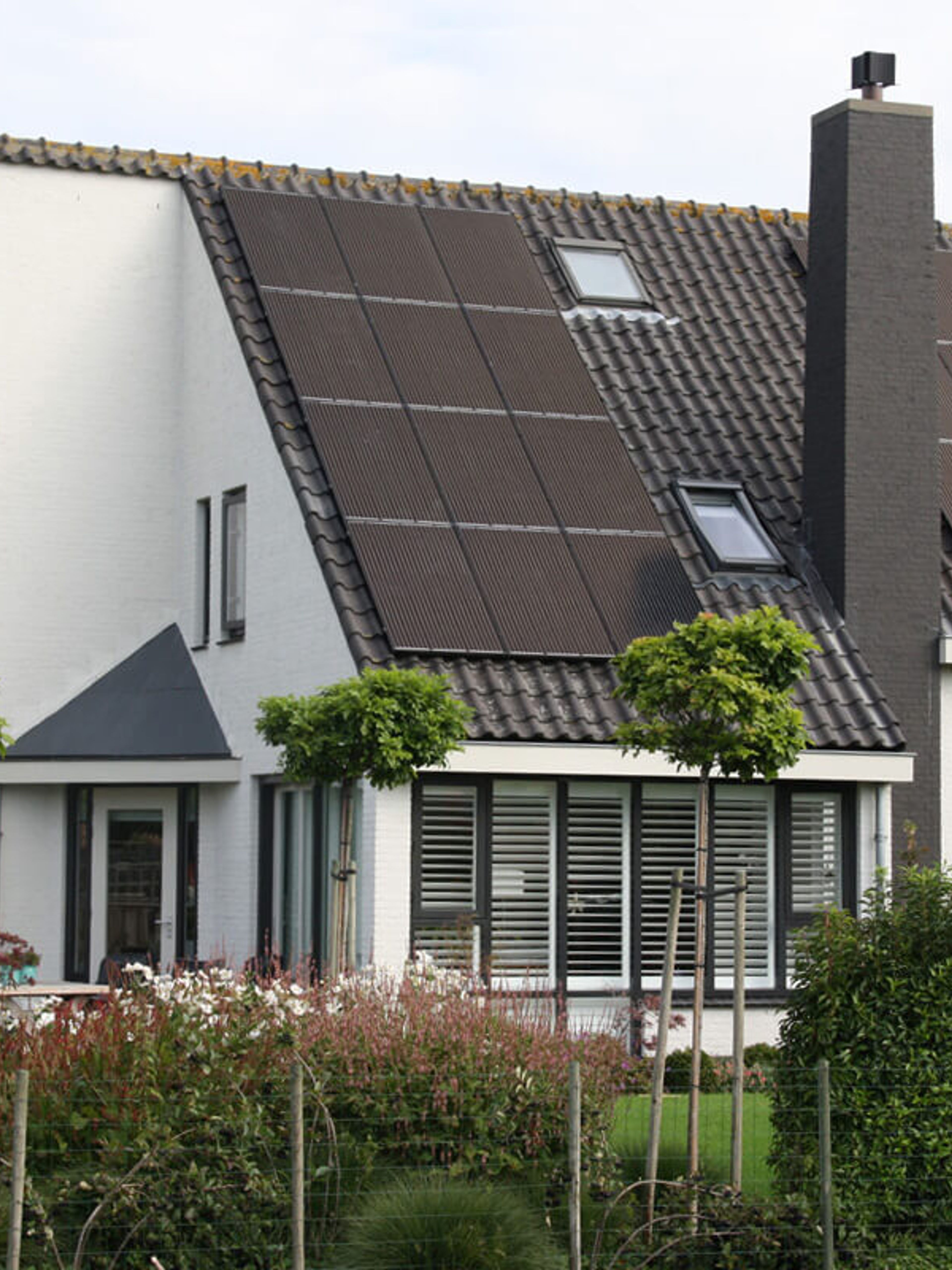 Wit geschilderde vrijstaande woning met donkere kozijnen en shutters