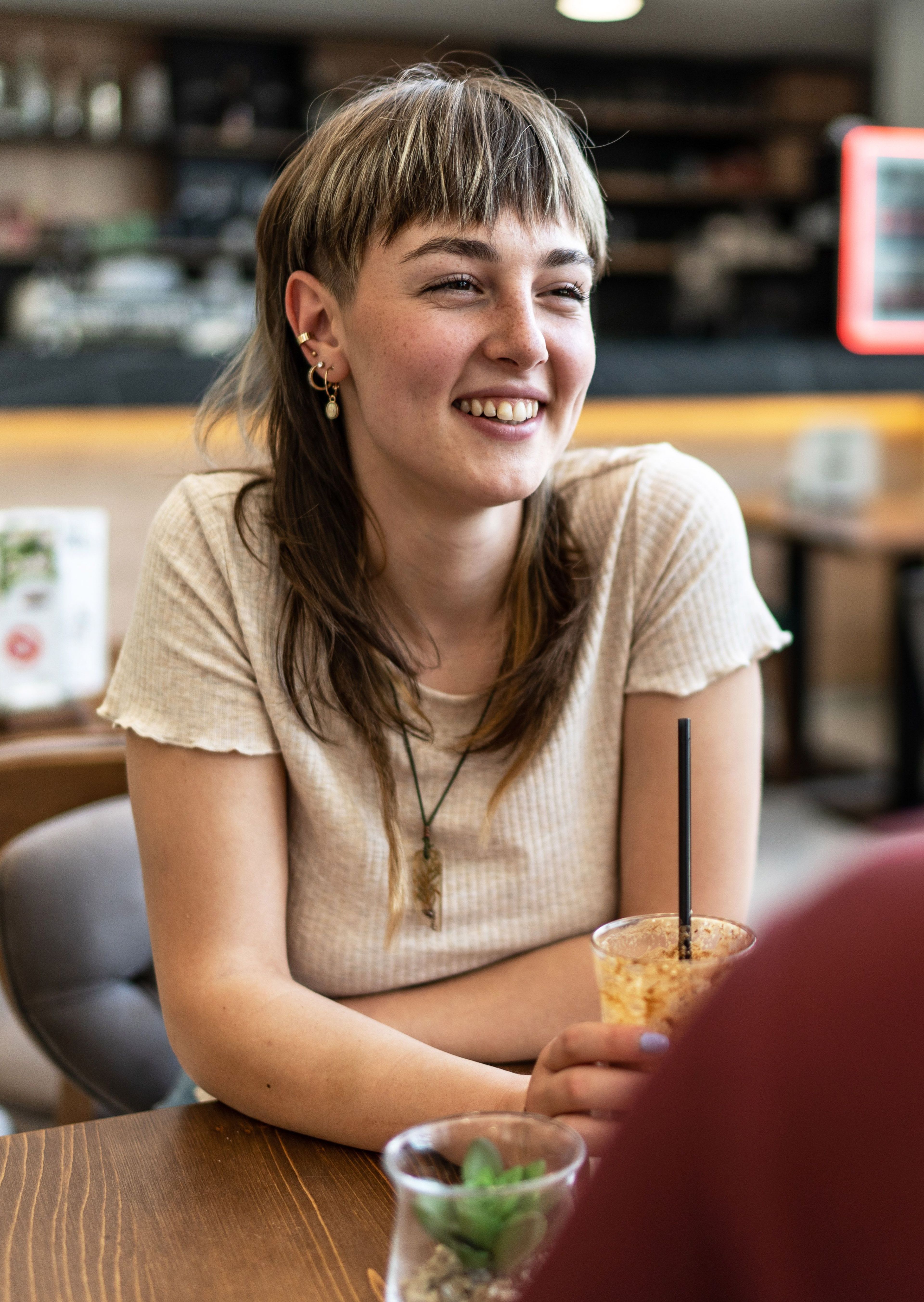 Jonge vrouw met een drankje en een glimlach.