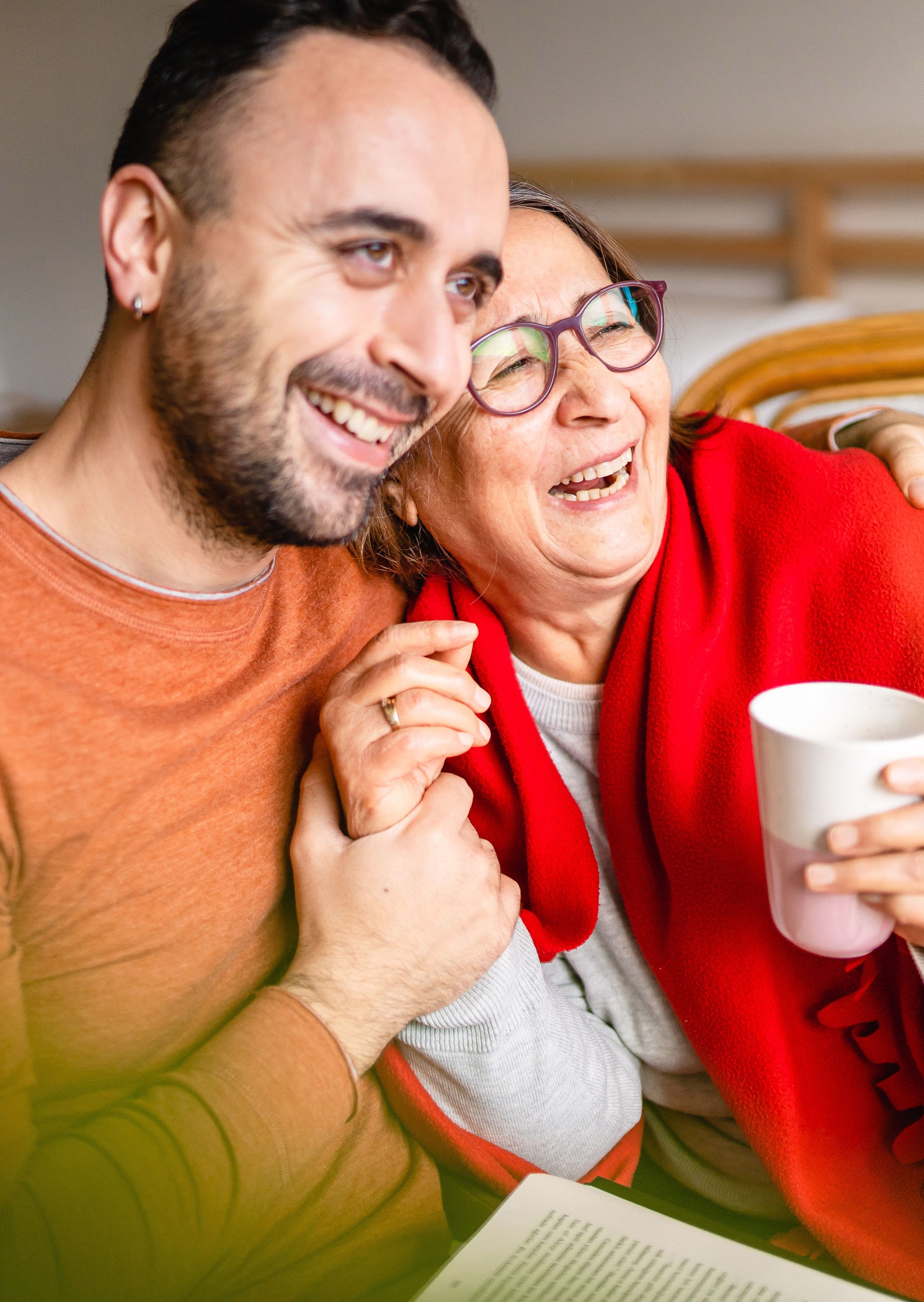 Een man en een vrouw lachen samen, knuffelend.
